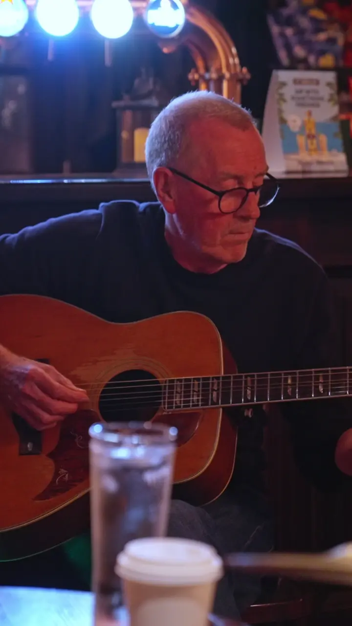 A guitarist playing at a table during the Thursday acoustic session.
